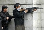 An unidenttified man fires an automatic weapon near the main government building in Bishkek, Kyrgyzstan, Wednesday, April 7, 2010. Police in Kyrgyzstan opened fire on thousands of angry protesters who tried to seize the Central Asian nation's main government building, after beating up dozens of police officers. At least four protesters were shot dead.