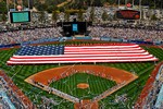 U.S. Navy sailors and Marines unfurl a football field-sized American flag at Dodger Stadium during the pre-game activities before a baseball game between the Los Angeles Dodgers and the San Francisco Giants in Los Angeles, Calif., April 14, 2009.