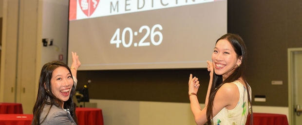 Twin medical students standing in front of a screen with a countdown clock