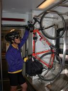 Picture of a person hanging a bike in a light rail vehicle.